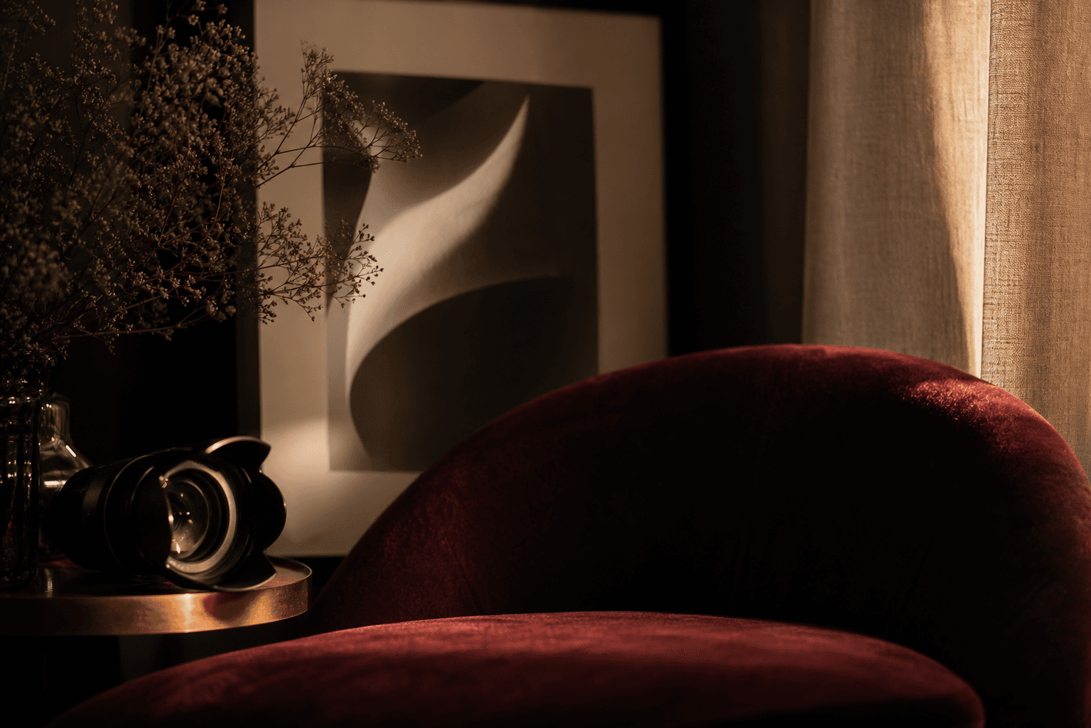 A velvet chair, camera lens, curtain, and framed abstract photograph